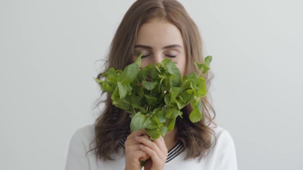 Retrato jovem mulher bonita cheirando verdes frescos em pé à mesa na cozinha moderna. Conceito de comida saudável. Profissão de nutri terapeuta, nutracêutico, nutricionista, treinador de bem-estar — Vídeo de Stock