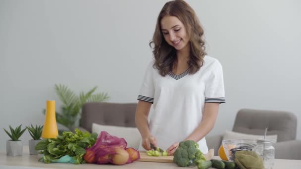 Joven habilidad linda mujer rebanando verduras con el cuchillo afilado en la mesa en la cocina. Concepto de comida saludable. Muchas frutas y verduras que yacen en primer plano — Vídeos de Stock