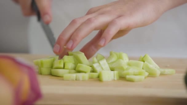 Fechar as mãos femininas cortando pepino com a faca na cozinha. Conceito de alimentação saudável . — Vídeo de Stock