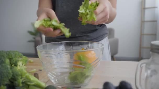 Female hands putting lettuce in the deep bowl. Unrecognizable woman cooking breakfast in the kitchen. Healthy lifestyle. Camera moving closer — Stock Video