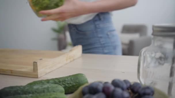 Figura borrosa de una joven mujer delgada tomando un tazón grande con ensalada de la mesa preparándose para comer. Chica feliz cocinando el desayuno en la cocina. Concepto de comida saludable. Profesión de nutracéutica . — Vídeos de Stock