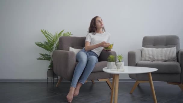 Junge schlanke Frau mit großer Schale mit Salat, die im Sessel ihr gesundes Essen genießt. gesunder Lebensstil. Beruf des Ernährungstherapeuten, Ernährungswissenschaftlers — Stockvideo