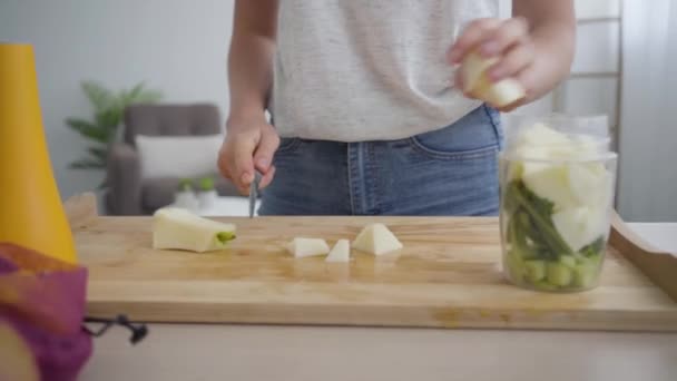 Primeros planos de las manos de una mujer joven cortando una manzana grande con el cuchillo afilado y poniéndola en el tazón en la cocina. Concepto de comida saludable. Profesión de nutri terapeuta, nutracéutico, nutricionista — Vídeo de stock