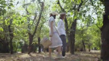 Güzel bir çift, parkta ya da bahçede el ele tutuşarak, duygusal olarak konuşuyorlar. Uzun saçlı ve güzel bir kadın dışarıda birlikte vakit geçiriyor. Retro tarzı. Yan görünüm