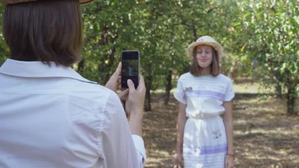 Ten muž fotografovat krásnou ženu v klobouku. Hezký pár tráví čas pohromadě v parku. Milovníci zábavy se baví venku. Retro styl. Střelba přes rameno — Stock video