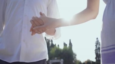 Parkta ya da bahçede el ele yürüyen çift. Erkek ve kadın açık havada birlikte vakit geçiriyor.