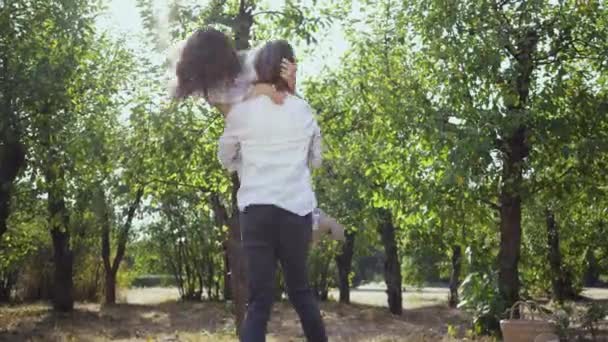 Šťastný mladý pár si spolu užijí v parku nebo v zahradě. Ten chlápek, co se točí s tou holkou. Volný čas, spojení s přírodou, vychutnávání slunečného letního dne. — Stock video