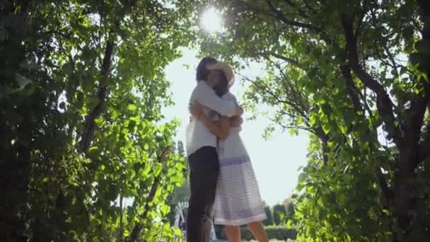 Szczęśliwa Młoda para przytulanie w parku lub ogrodzie. Mężczyzna i kobieta spędzają razem czas. Wypoczynek na świeżym powietrzu, enjoynig słoneczny letni dzień. — Wideo stockowe