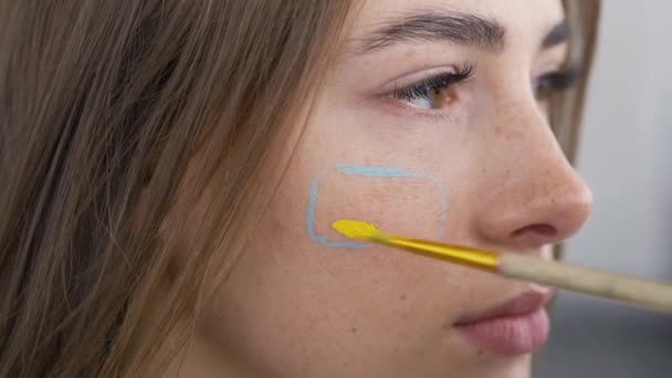 Retrato detalhado de uma jovem mulher bonita. Artista pintura no rosto meninas usando pequena escova macia. Conceito de arte corporal. Arte bonito em um corpo humano — Vídeo de Stock