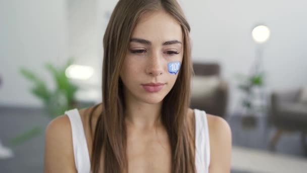 Retrato de una mujer joven y atractiva sosteniendo el teléfono y la tableta en las manos y sonriendo mirando a la cámara. Caja de mensaje azul pintada en la cara de las chicas. Concepto de redes sociales. Adicción a los aparatos . — Vídeos de Stock