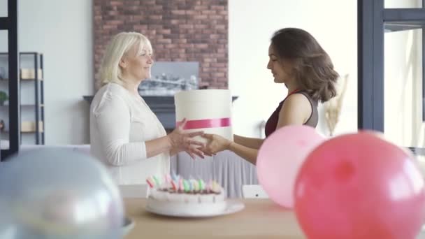 De dochter geven moeder de huidige doos. Vrouwen knuffelen en glimlachen. Verjaardag viering concept. Zorgzame vrouw geven aanwezig aan moeder of grootmoeder. — Stockvideo