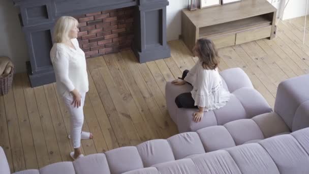 Junge Frau streitet mit ihrer Mutter, während sie auf dem Sofa im großen Wohnzimmer sitzt. schwierige familiäre Beziehung, Missverständnisse zwischen verschiedenen Generationen — Stockvideo