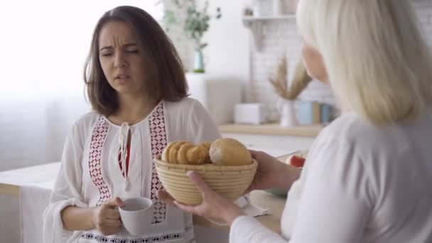 Retrato de una joven atractiva bebiendo té o café y hablando con su madre. La chica compartiendo sus secretos con mamá. Amistosa familia pasar tiempo juntos . — Vídeos de Stock