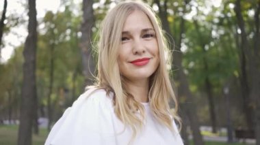 Çekici sarışın kadın kameraya bakıyor ve uzak. Güzel model gülümsüyor. Boş zaman açık havada, doğa ile bağlantı.