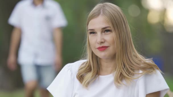 Hermosa mujer caucásica sentada en el parque o bosque, el hijo viene por detrás y abrazando a su madre. Feliz familia pasando tiempo juntos. Día soleado al aire libre . — Vídeos de Stock