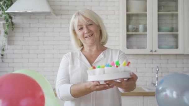 Seniorin zeigt Kuchen, der für ihr Kind oder Enkelkind vorbereitet wurde. Geburtstagsfeier. Fürsorgliche Oma bereitet Geschenk vor. — Stockvideo