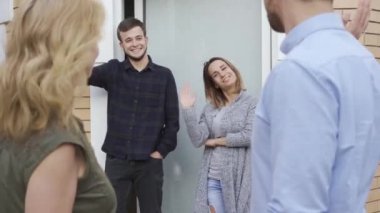 Hoş beyaz bir aile kapıda duruyor, el sallıyor ve gülümsüyor. Yeni komşularını terk ederek misafirler. Evli çiftler birbirlerine veda.