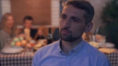 Olgun düşünceli adam tatil kutlayan gençlerin gürültülü şirket sırtı ile ön planda oturuyor. Yalnızlık kavramı.