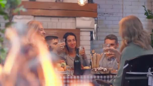 Lycklig kaukasiska familj pratar och leende sitter vid bordet i bakgrunden. Flamma brinnande i förgrunden. Vänlig familj fira semester. — Stockvideo