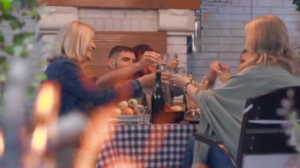Η παρέα των ανθρώπων που πίνουν αλκοόλ και χαμογελούν κάθονται στο τραπέζι στο παρασκήνιο. Φλόγα καίγεται στο προσκήνιο. Φιλική οικογένεια γιορτάζοντας διακοπές — Αρχείο Βίντεο