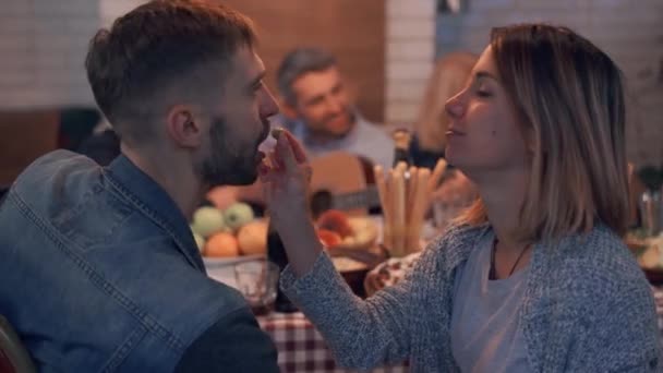 Hermosa mujer caucásica alimentando a su novio con aceitunas en primer plano. Hombre maduro tocando la guitarra y cantando en el fondo . — Vídeos de Stock