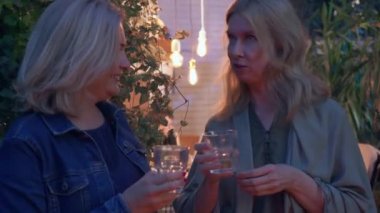 İki sarışın olgun kadın sohbet edip alkol içiyor. Komşular yaz akşamı dedikodu yapar. Dostluk kavramı, iyi komşu ilişkisi.