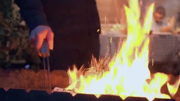 Zbliżenie męskich rąk co ogień do grilla zbliżenie. Człowiek przygotowuje się do gotowania mięsa dla firmy na zewnątrz. Czas wieczorowy — Wideo stockowe