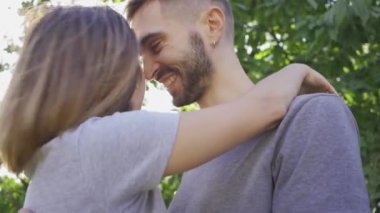 Genç adam ve kadın öpüşme ve yaz bahçesinde güneş ışığında sarılma portresi. Mutlu genç aile dışarıda dinleniyor. Mutluluk kavramı, ilişki, şefkat