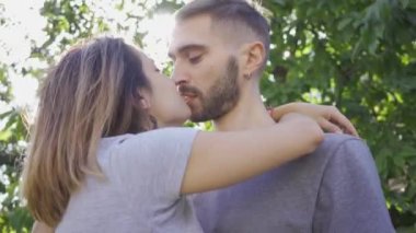 Portre sevimli genç adam ve kadın öpüşme ve yaz bahçesinde güneş ışığında sarılma. Mutlu genç aile dışarıda dinleniyor. Mutluluk kavramı, ilişki, şefkat