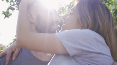 Yaz bahçesinde güneş ışığında eşine sarılan yakışıklı genç adamın portresi. Mutlu genç aile dışarıda dinleniyor. Mutluluk kavramı, ilişki, şefkat