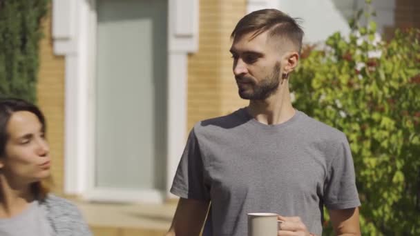 Atractiva mujer caucásica y hombre guapo de pie frente a la casa grande. Besar pareja . — Vídeos de Stock