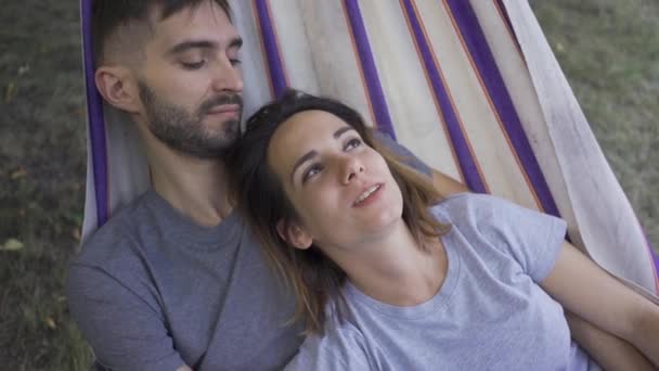 Heureuse jeune famille caucasienne couchée dans un hamac dans le jardin se détendre ensemble. Aimer couple ensemble à l'extérieur. Loisirs d'été — Video