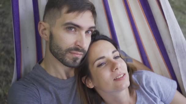 Rosto de feliz jovem família caucasiana deitada em rede no jardim relaxando juntos. Casal amoroso juntos ao ar livre. Lazer de verão — Vídeo de Stock