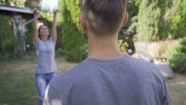 Genç adamın karısıyla dışarıda top oynarken ki görüntüsü. Aktif boş zaman. Yaz evinde dinlenen mutlu çift — Stok video