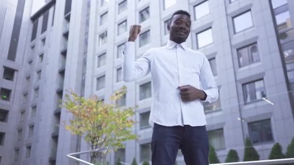 Felice gioioso uomo afroamericano in camicia bianca alzare i pugni nei gesti di vittoria mentre in piedi sulla strada della città. Uomo d'affari o manager ha avuto grandi notizie — Video Stock