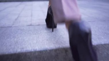 Açık havada merdivenlerden yükselen kostümlü zarif kadının yakın ayakları. Sokakta yürüyen yüksek topuklu ayakkabılı iş kadını. Kızı takip eden kamera