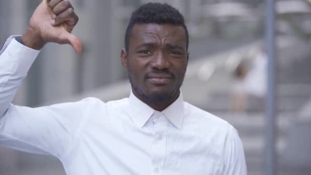 Zblízka pohledného afroamerického muže v bílé košili, který ukazoval palec na kameru, zatímco stojí na městské ulici. Obchodník nebo manažer pro muže nespokojena s jeho prací. — Stock video