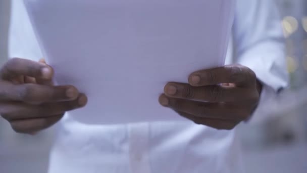 Nahaufnahme eines afrikanisch-amerikanischen Mannes im weißen Hemd, der Dokumente liest. männliche Geschäftsleute oder Manager, die im Büro arbeiten. von unten — Stockvideo