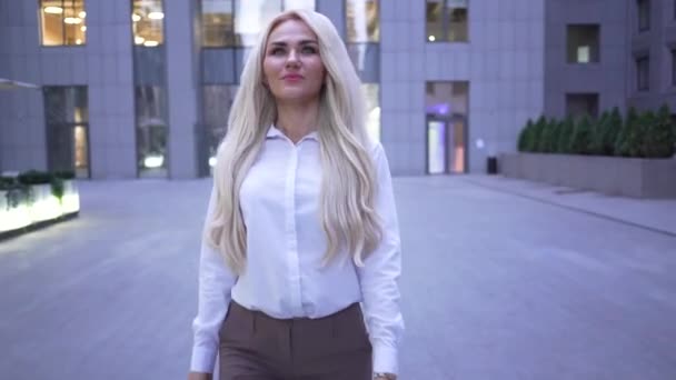 Blond smiling caucasian businesswoman walking on the city street and smiling. Young professional going for lunch. — Stok video