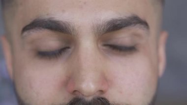 Kameraya bakan sakallı ve bıyıklı çekici kahverengi gözlü adamın aşırı yakın çekimi. Yakışıklı bir adamın portresi.