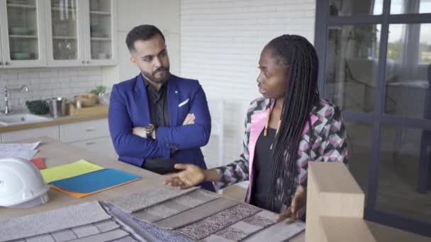 Döşemeve mobilya tarzı seçerken memnun çok kültürlü çift konuşuyor. Beyaz adam ve Afro-Amerikan kadın evlerini dekore ediyor. İç tasarım. — Stok video