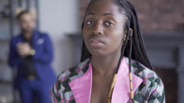 Portré szomorú afroamerikai nő a problémás bőrt állva az előtérben, míg a férje a háttérben járás. Férj nem figyel a feleségének — Stock videók