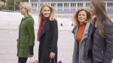 Sokakta mutlu bir şekilde konuşan dört güzel kız arkadaş. Şehirde yürüyen alışveriş poşetleri olan dört moda kadını. Birlikte boş zaman. Kızlar kendi alımları zevk