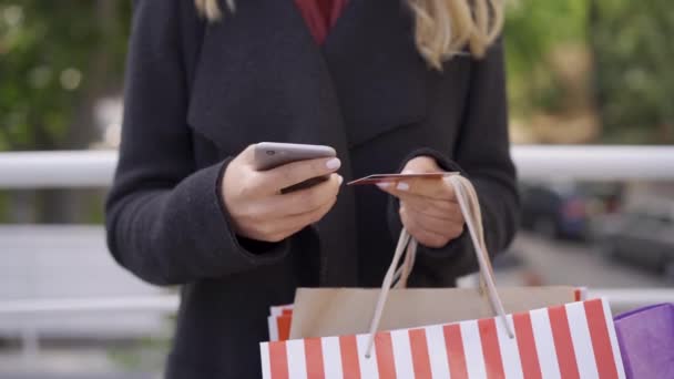 Close up de mulheres caucasianas mãos fazendo pagamento on-line usando seu telefone celular e cartão de crédito. Pagamento fácil, tecnologias modernas . — Vídeo de Stock