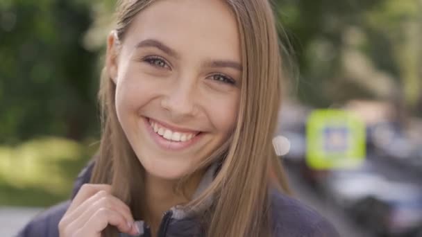 Närbild av attraktiva unga kaukasiska kvinna med långt brunt hår leende glatt tittar på kameran. Känslor, lycka, gott humör. — Stockvideo