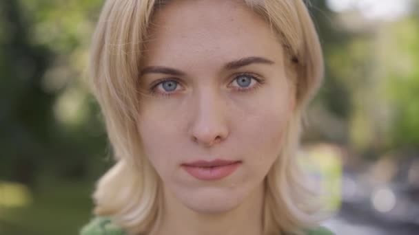 Young blond caucasian woman with medium length haircut looking at camera. Portrait of a beautiful grey-eyed girl. — Stock Video