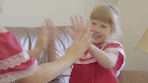 Lächelndes süßes blondes Mädchen in roten Nachthemden, das mit ihrer Mutter spielt. hübsches Kind beim Kuchenspielen mit einer erwachsenen Frau. — Stockvideo