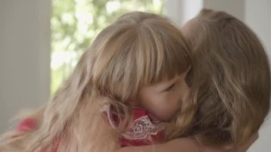 Uzun saçlı ve evde sarılan küçük kızı ile mutlu sarışın beyaz anne yakın çekim. Annelik, çocukluk, bir ebeveyn kavramı. İçeride boş zaman. Mutlu aile