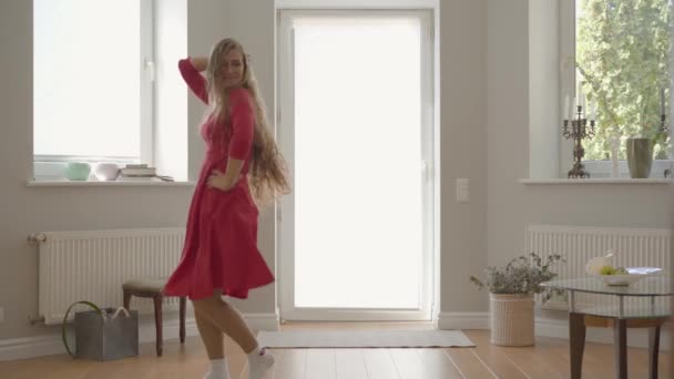 ブロンドの白人の母と娘は、手をつないで自宅で踊る同じ赤いドレスを着ています。母性の概念、子供時代、一人の親。幸せな家族が一緒に過ごす日. — ストック動画