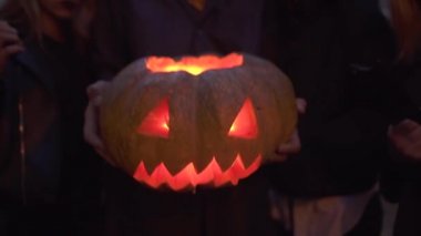 Uzun boylu yakışıklı adam yakın içinde bir ışık ile halloween balkabağı tutan, üç güzel kız yanında duruyor. Kötü görünüyor ile kameraya bakarak yüzleri korkunç makyaj ile insanlar. Alt görünüm